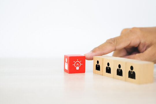 Hand choose human with light bulb icon on cube wooden block stack. Concepts of people business team creative thinking and resources for personnel leader and teamwork or leadership team player.