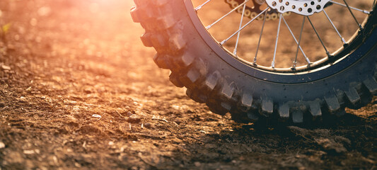 Part of a dirt bike on a dirt road in a cornfield with warm light. Copy space.