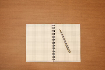 Close-up notebook or note book diary with a pen or pencil on top view wooden desk or boardroom table for meeting notes.