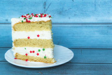 A slice of vanilla cake with a layer of buttercream located on the left. Close-up. Red-green dusting