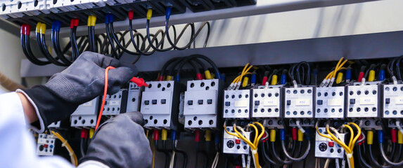 Electricity and electrical maintenance service, Engineer using measuring equipment checking electric current voltage at circuit breaker terminal block and cable wiring main power distribution board.