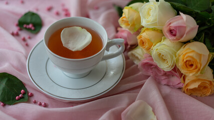 A cup of tea and a bouquet of roses on a pink background. Romantic, sweet, dating concept.