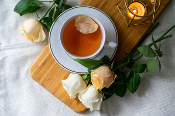 A cup of tea and a bouquet of roses on a white background. Warm and pastel tones. Top view. Still life