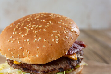 A closeup view of the top of a sesame bun, featured as part of a bacon cheeseburger.