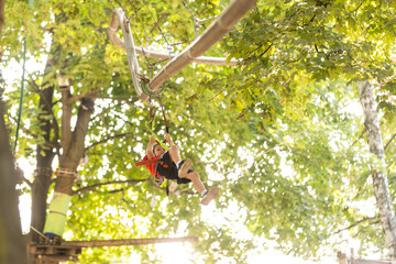 Adventure climbing high wire park - little boy on course in mountain helmet and safety equipment