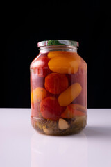 canned vegetables in a jar on a white table and black background