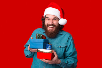 Joyful bearded man is holding some gift boxes for Christmas.