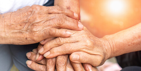 Fototapeta premium Caregiver, carer hand holding elder hand in hospice care background. Philanthropy kindness to disabled old people concept.Happy mother's day.