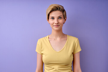 Calm Caucasian Short-haired Woman In Casual Wear Looking At Camera Confidently, Wearing Casual Yellow T-shirt Copy Space, Isolated On Purple Studio Background, People Lifestyle Concept.