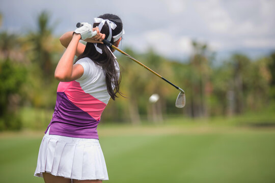 Asian girls are playing golf on a sunny day on the beautiful green golf course.