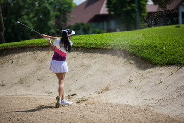 Asian girls are playing golf on a sunny day on the beautiful green golf course.