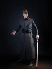A villain with a red lightsaber, a young man in a long robe does fighting poses,
