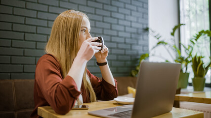 Young blond woman enjoying drinking coffee in cafe before work, morning ritual