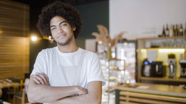 Biracial young man standing in cafe arms crossed on chest, small business owner