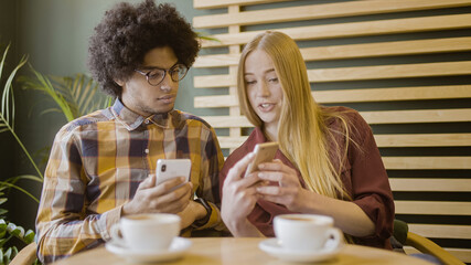 Girlfriend showing boyfriend new mobile app on smartphone, friends talking about gadgets