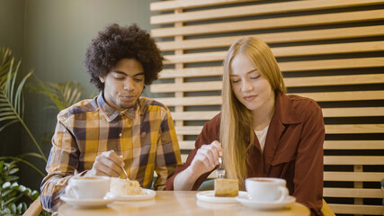 Multiethnic friends tasting desserts in cafe, enjoying food and coffee, relax