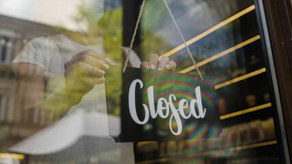 Shop employee in face mask turning putting closed door sign on, lockdown restrictions - Powered by Adobe