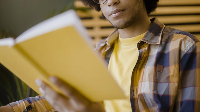 Male student reading book and drinking coffee, preparing for tests, studying