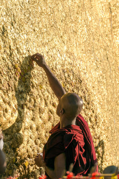 Myanmar (formerly Burma). Kyaiktiyo. State Mon. Sacred site of the golden rock. Monk depositing gold leaves