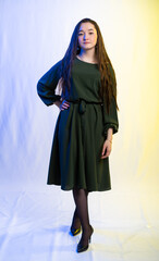 Fototapeta premium full-length portrait of a girl. model in a green dress, black shoes. long curly hair. colored background.
