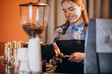 Female barista making coffee in a coffee machine