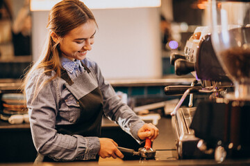 Female barista making coffee in a coffee machine