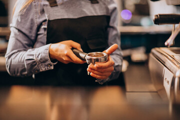 Female barista making coffee in a coffee machine