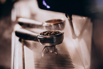 Fototapeta na wymiar Coffee beans in a metallic cup in a coffee machine