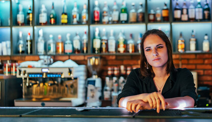 Portrait of young attractive woman bartender behind the bar counter