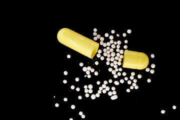 medicine poured from a capsule on a black background. macro photo