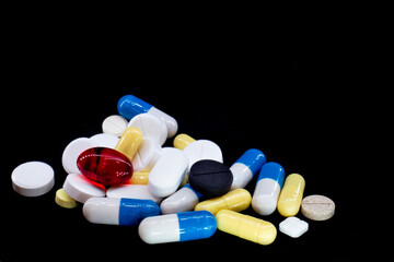 pills of different shapes and colors on a black background. macro photo