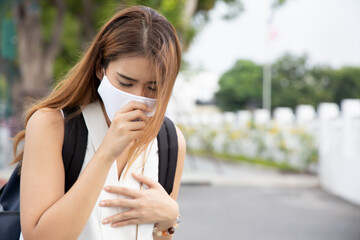 Vaccinated young asian woman wearing face mask and getting sick from coronavirus breakthrough...