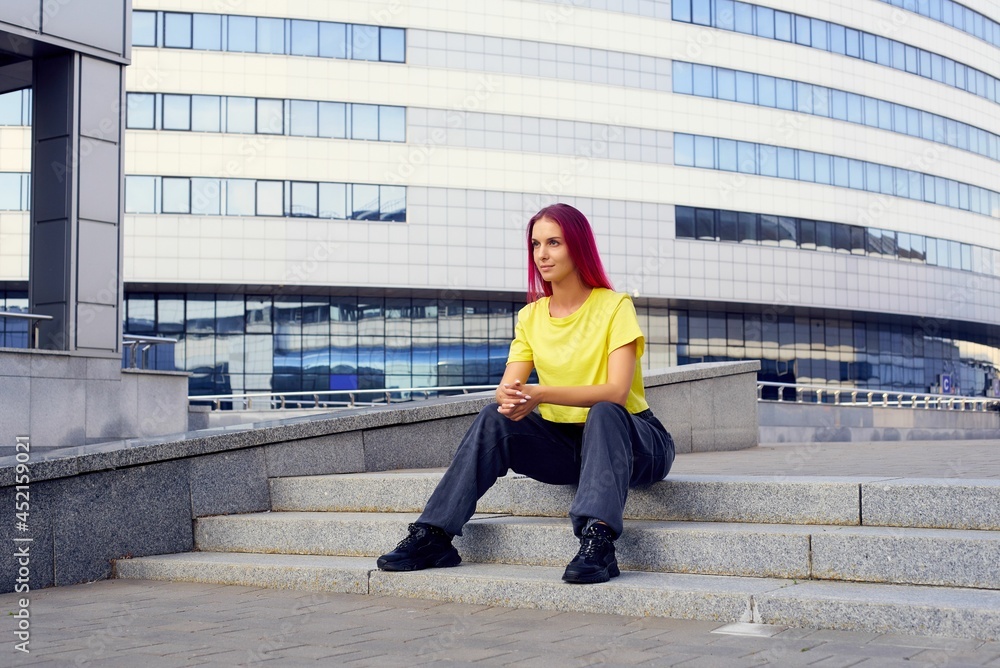 Wall mural girl in sports clothes is sitting on the steps after a workout in the city