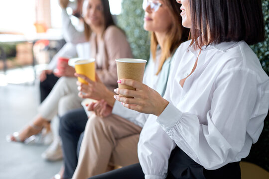 business, communication and education concept. group of colleagues drinking coffee during break time, close-up photo of woman hands sitting with cup, having talk or listening, in formal wear