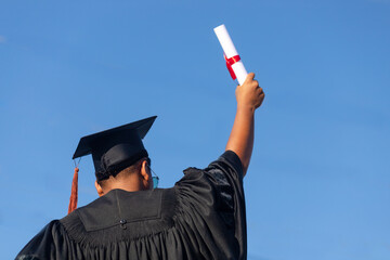 The graduates raised their hands to celebrate graduation with a certificate in hand and her...
