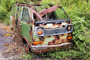 草むらの中で見捨てられて朽ち果てたボロボロの自動車