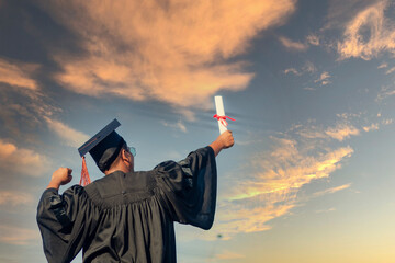 The graduates raised their hands to celebrate graduation with a certificate in hand and her...