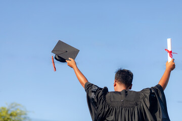 The graduates raised their hands to celebrate graduation with a certificate in hand and her...