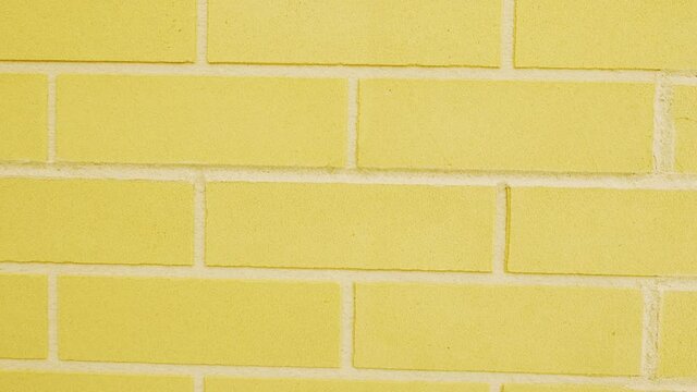 Motion upward high wall of yellow bricks with white finishing at empty construction site on bright summer day closeup