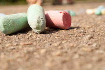 multi-colored crayons for drawing on the asphalt.
Children draw rainbow colors outdoors with chalk on a sunny summer day. Creative development of children.
Place for your text.