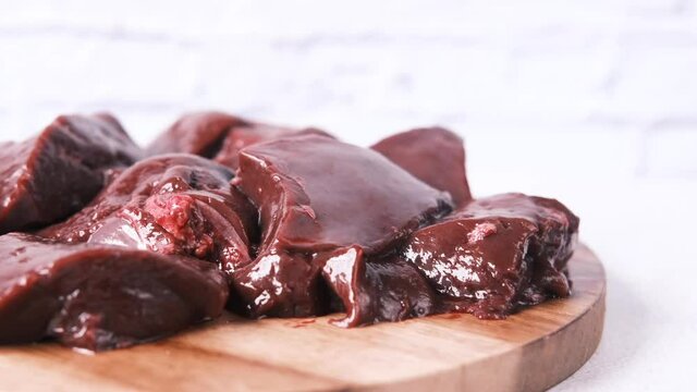 Raw liver on a chopping board on table .