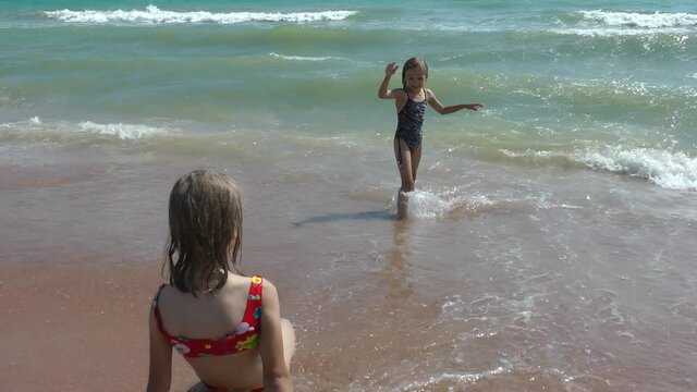 Children girls play on the seashore and have fun, summer happy time, rest and recreation.