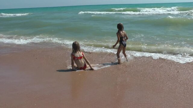 Children girls play in the waves of the sea and have fun, summer happy time, relaxation and recovery.