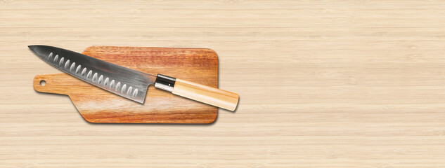Traditional Japanese gyuto chief knife on a cutting board. Wooden background banner