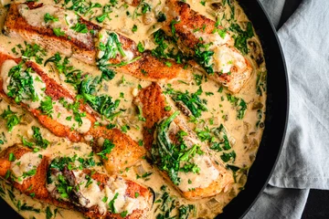 Fotobehang Creamy Garlic Butter Tuscan Salmon in a Skillet: Salmon fillets in a creamy parmesan sauce with spinach and sun-dried tomatoes © Candice Bell