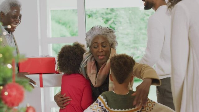 Family greeting grandparents at front door ss they arrive with presents to celebrate family christmas at home - shot in slow motion