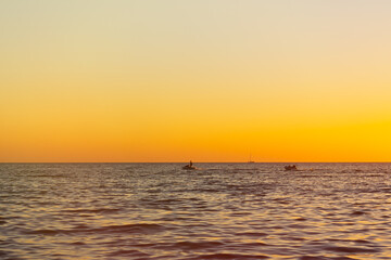 Boat sea raft tablet at sunset. A young man on a boat rides people on an inflatable round mattress on the sea. A risky sea attraction. The concept of summer holidays, vacations, hot sultry August.