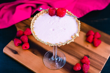 Raspberry Cheesecake Martini with a Berry Garnish: Raspberry cheesecake martini in a cocktail glass rimmed with graham cracker crumbs