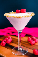 Raspberry Cheesecake Martini with a Berry Garnish: Raspberry cheesecake martini in a cocktail glass rimmed with graham cracker crumbs