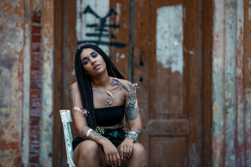 Naklejka premium Portrait of a young beautiful tattooed girl with box braids hairstyle